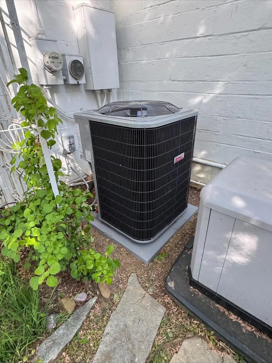 Outdoor HVAC condenser beside a masonry wall